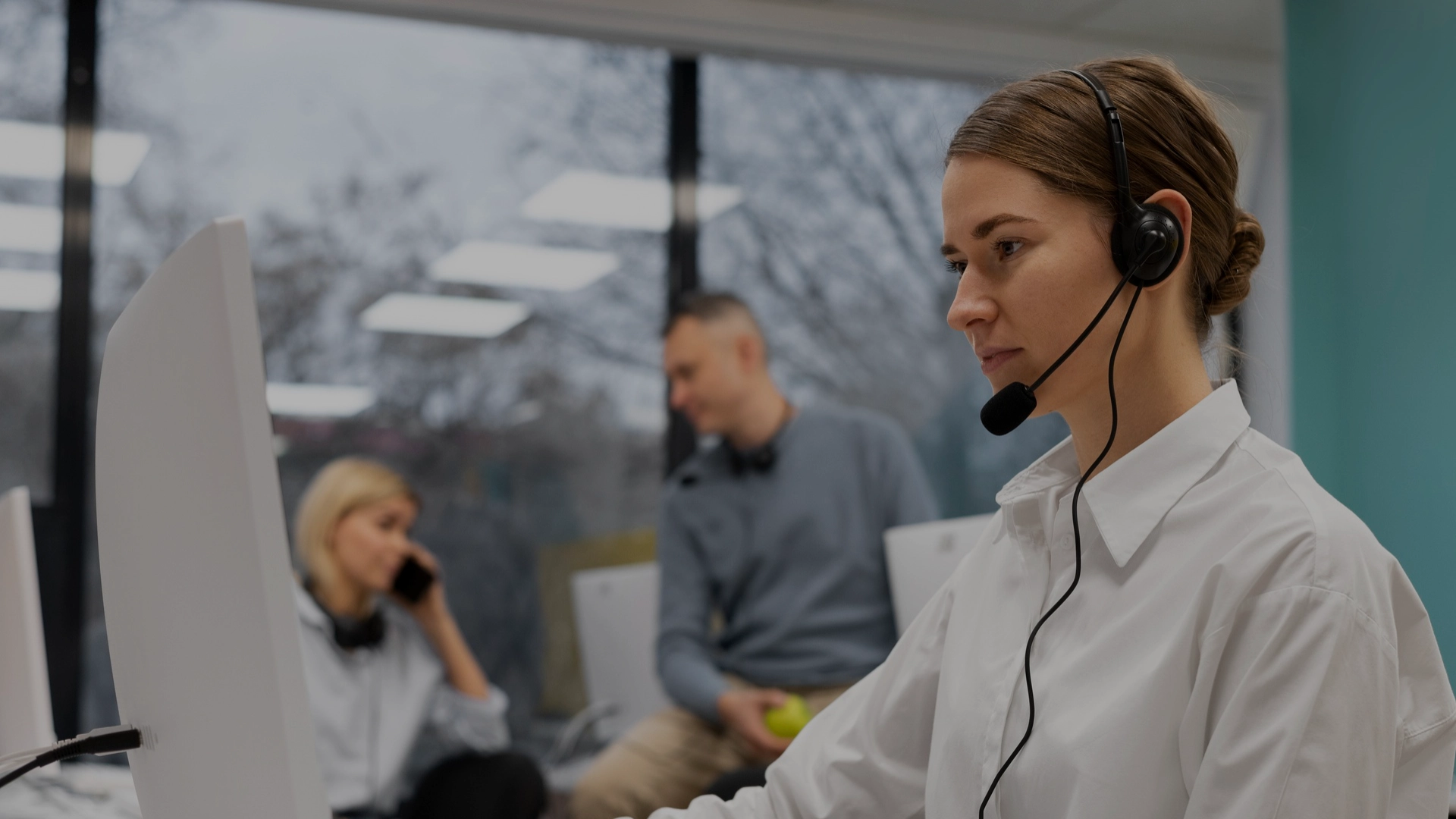 Customer service representative wearing a headset at a call center, assisting a client over the phone